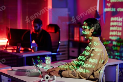 Preview: Contemporary young software engineer sitting by workplace in front of laptop