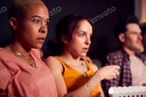 Preview: Group Of Friends Eating Popcorn Sitting On Sofa At Home Watching Horror Movie Together