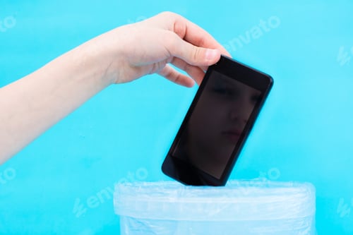 Preview: Digital detox concept. Children's hand throws a smartphone into the trash. Gadget addiction