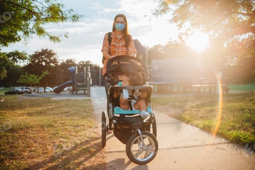 Preview: Mother with mixed race children at take a stroll through a playground at sunset, mother wearing mask