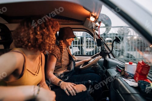 Preview: Two friends sharing a laugh on a road trip at dusk