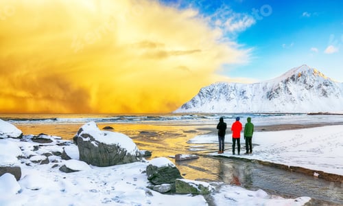 Preview: Group of tourist looking fabulous winter scenery on Skagsanden beach with illuminated clouds