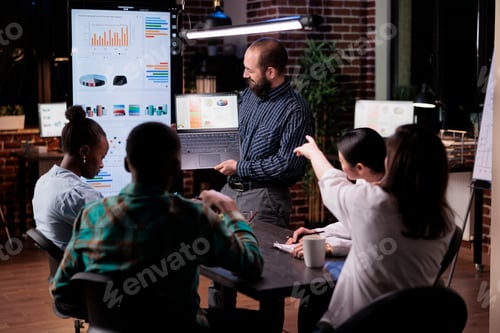 Preview: Office worker holding laptop with business presentation looking at screen while coworker is pointing