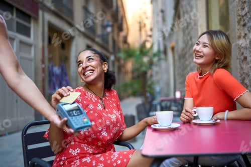 Preview: Lesbian couple paying in a coffee with credit card