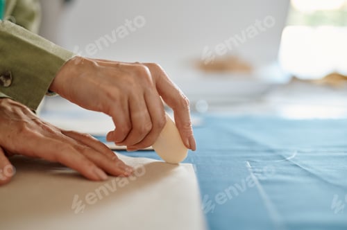 Preview: Dressmaker measures cloth on the table in workshop