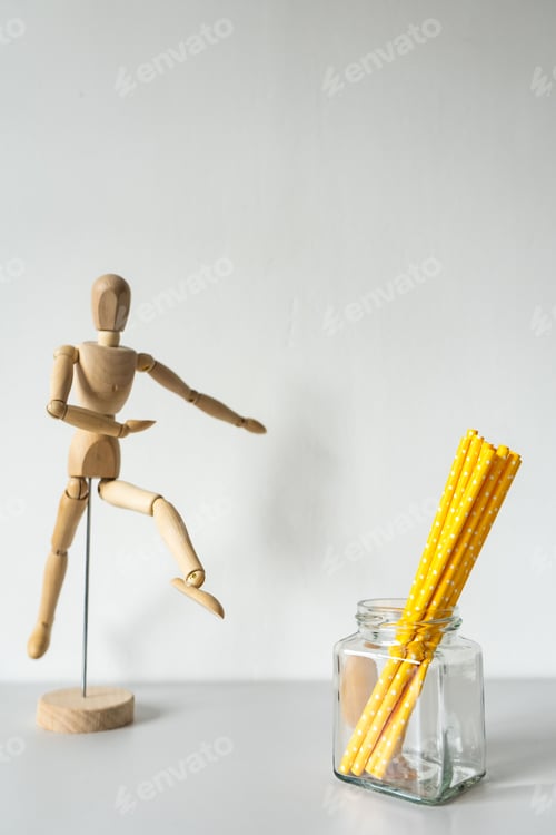 Preview: Wooden human mannequin and yellow paper straws isolated on white background