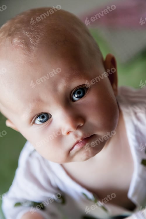 Preview: Portrait one year old blue eyes child look at camera in stylish wear from crib