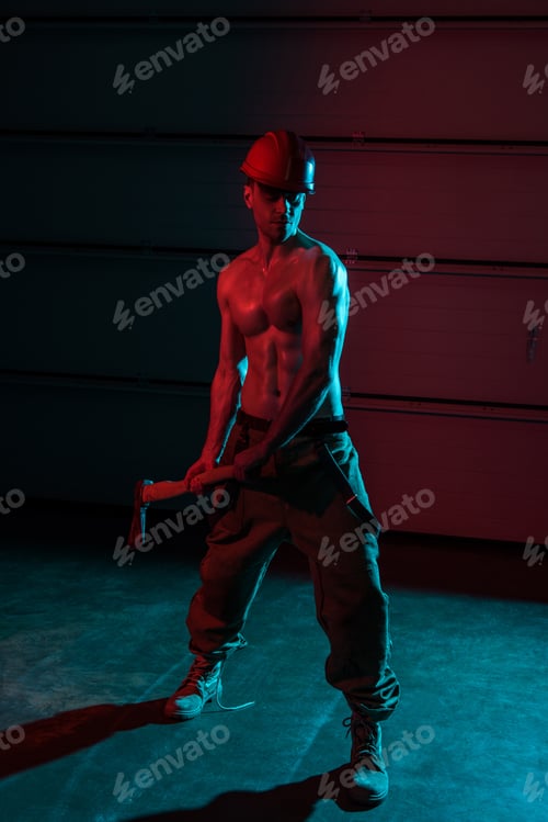 Preview: full length view of sexy shirtless fireman holding flat head axe in darkness