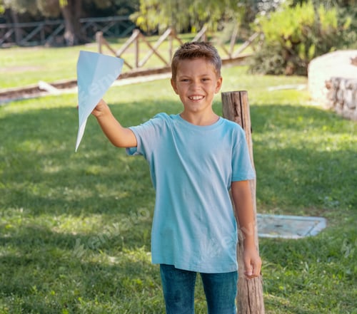 Preview: Happy Preschooler boy plays with a paper plane in a park