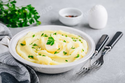 Preview: Mashed Potatoes with butter and fresh parsley in a white bowl on gray stone background.