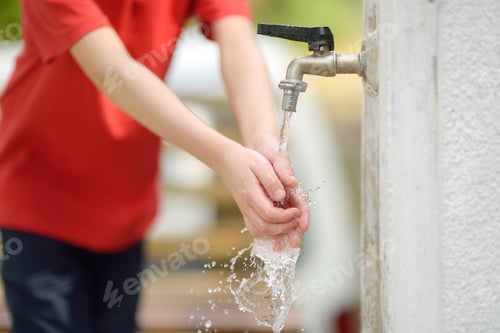 Preview: Closeup photo of child washing hands in a city fountain