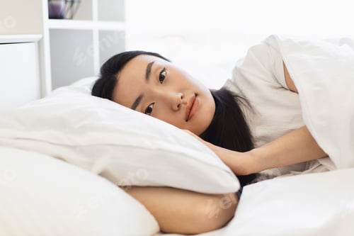 Preview: Asian woman relaxing in bed with peaceful expression