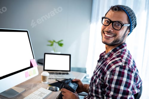 Preview: Attractive hipster smiling at camera while working at desk