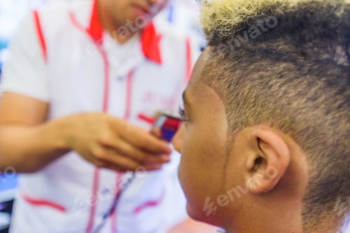 Preview: Hairdresser cutting teenage boy's hair in barbershop