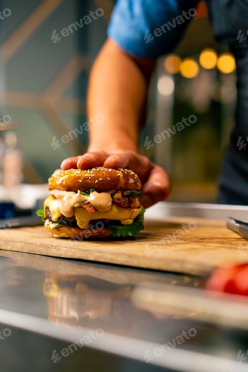 Preview: A close-up of a chef preparing a burger with beef patty with vegetables and cheese in the kitchen
