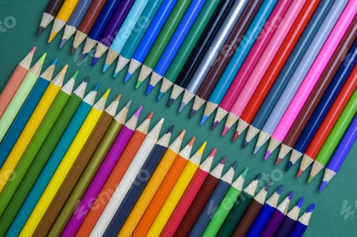 Preview: Color pencils on green background. Arrangement of multicolored pencils. Top view. Close-up.