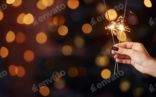 Preview: Close up view of woman's hand with sparkler indoors at christmas holidays