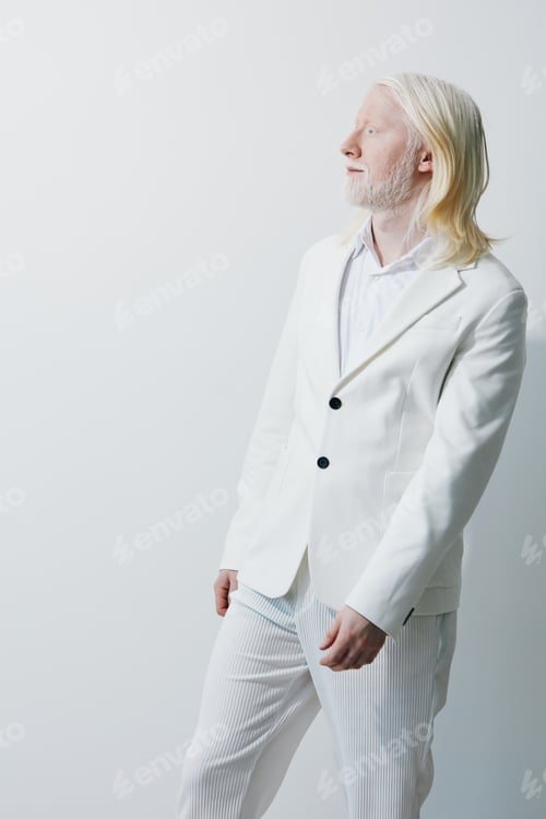 Preview: Stylish man in a white suit posing against a minimalist light background for fashion photography