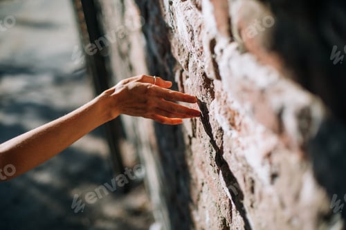 Preview: Woman’s hand on a bricks wall background
