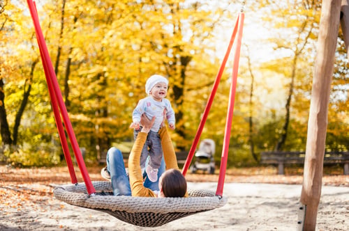 Preview: Happy baby girl relaxing with her mother on a swing in autumn