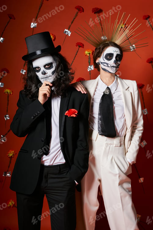 Preview: couple in scary skeleton makeup and festive attire on red backdrop with flowers, dia de los muertos