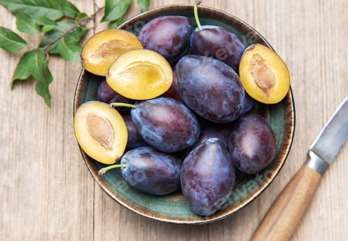 Preview: Fresh ripe plums in bowl on wood surface