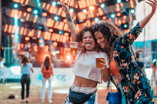 Preview: Two beautiful friends drinking beer and having fun on a music festival