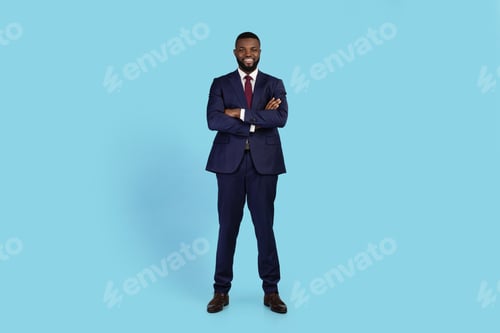 Preview: Portrait Of Confident Young Black Businessman In Suit Standing With Folded Arms