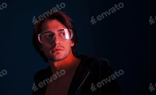 Preview: Beautiful long haired hot man in glasses is in the studio with blue neon lighting