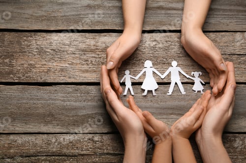Preview: Parents and child protecting paper cutout of family at wooden table, top view. Space for text