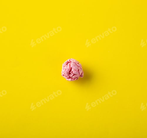 Preview: Crumpled pink paper ball symbolizing rejected ideas on yellow background