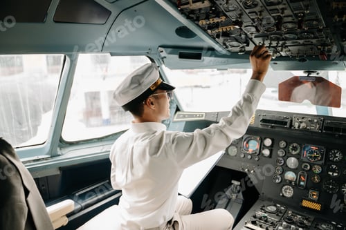 Preview: Asian Confident male pilot in uniform leaning at the passenger seat while standing inside