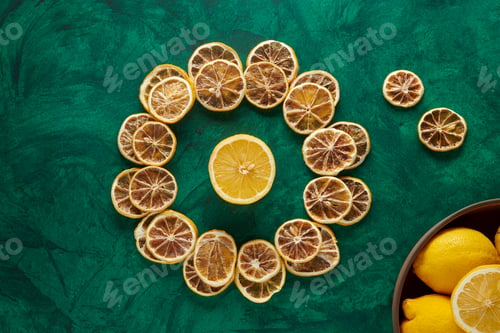 Preview: Dried Lemons on a Circle on a Green Background with Fresh Lemons in a Wooden Bowl