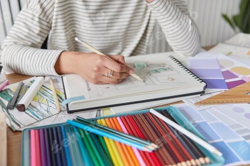 Preview: Cropped shot of unknown creative woman draws picture in album engaged in favorite activity develops