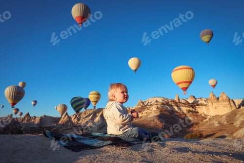 Preview: A child enjoying the breathtaking view of hot air balloons over Cappadocia fairy chimneys at sunrise