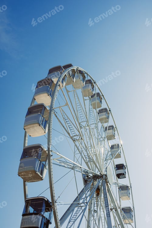 Preview: A large Ferris wheel rises into the air with cabins against a blue sky