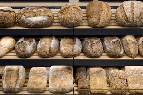 Preview: Various types of traditional homemade bread on the wooden shelves of a bakery store