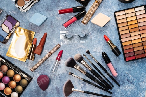 Preview: makeup brushes, decorative cosmetics, false eyelashes on a blue background. the view from the top