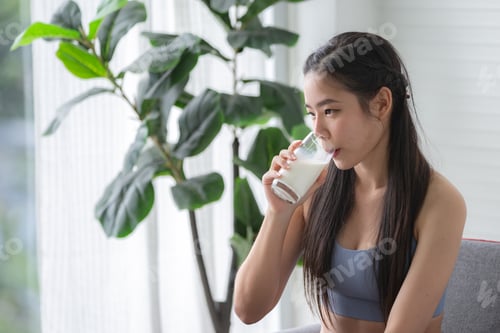 Preview: young beautiful woman drinking a fresh milk for body health care, smile girl holding glass of milk