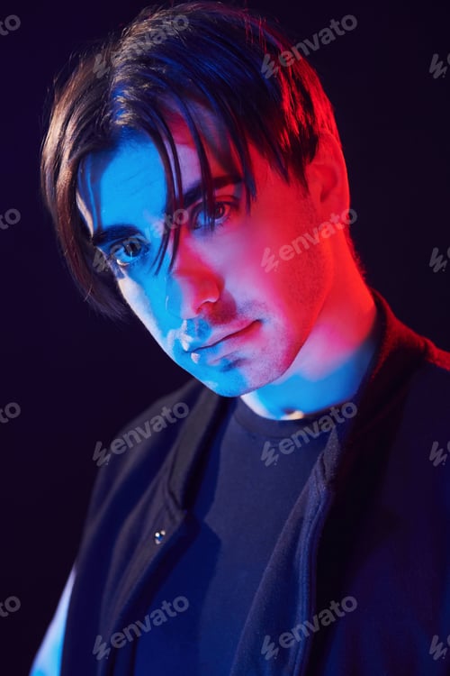 Preview: Looking into camera. Man standing in the studio with neon light
