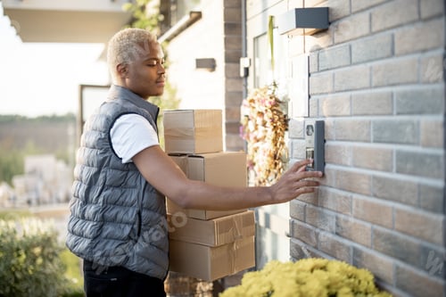Preview: Delivery man with parcels ringing in doorbell