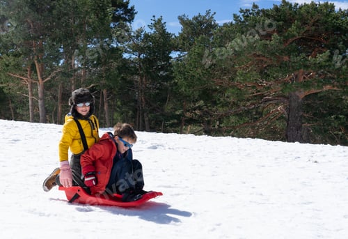Preview: Kids enjoying winter playing on a red sled