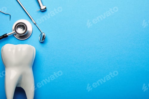Preview: flat lay with tooth model, stethoscope and sterile dental instruments arranged on blue backdrop