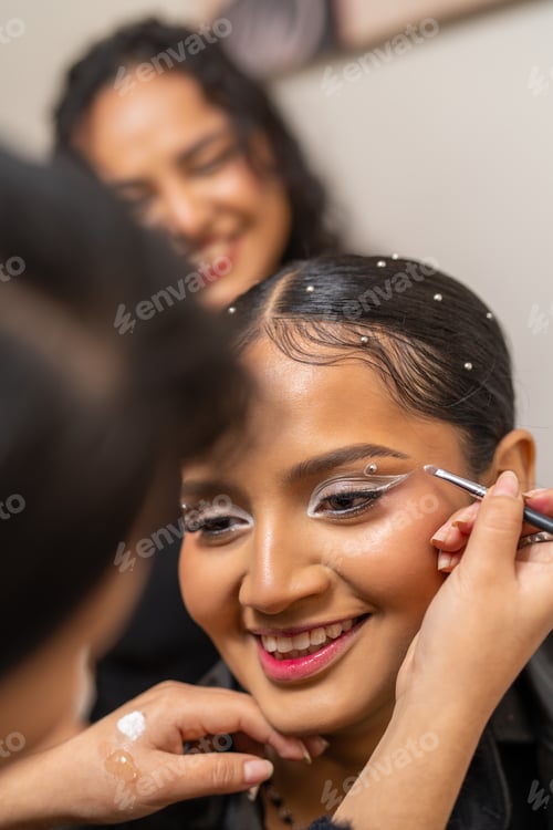 Preview: Make up artist applying eyeshadow on a smiling customer in a beauty salon