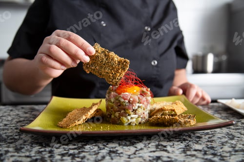 Preview: Unrecognizable woman serving tuna tartare with crouton