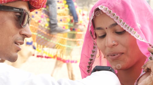 Preview: Closeup of an Indian couple in traditional outfits. The man showing the girl his smartwatch.
