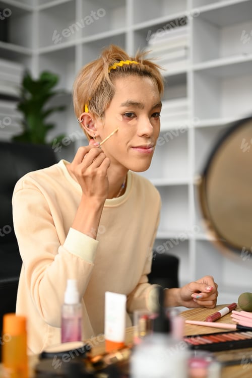 Preview: Young male make up artist vlogger or blogger applying concealer under his eye.