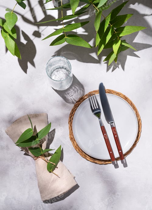 Preview: Celebration table setting with a light empty plate, a glass, and a napkin with eucalyptus branches