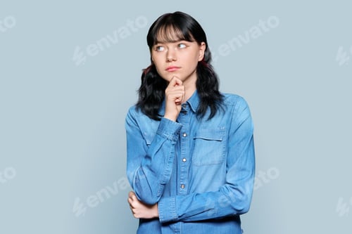 Vista previa: Portrait of pensive young female looking away on gray isolated background