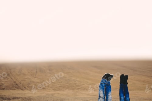 Preview: A women and man feet raised up high in the air. Shoot in field on autumn time. Place for inscription